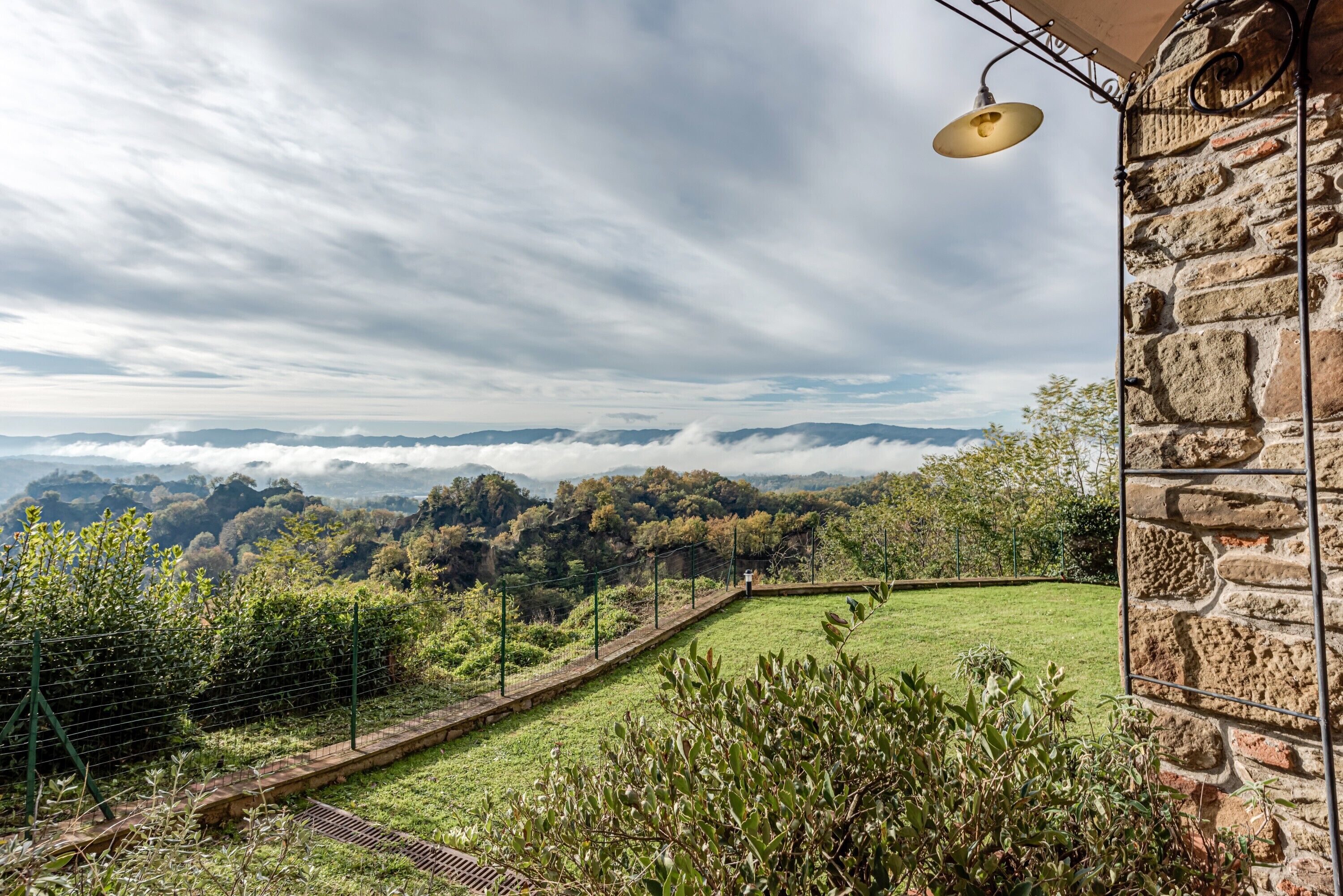 A stone building with a view of a grassy landscape and distant mountains.