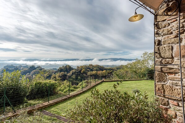 A stone building with a view of a grassy landscape and distant mountains.