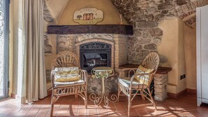 A stone fireplace with a 'Welcome Home' sign, two wicker chairs, and a small table. - Apartment 'Il Nido' with Shared Pool, Wi-Fi and Air Conditioning (Pian di Scò)