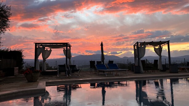 A poolside area with a sunset view, lounge chairs, and a pergola structure. - Apartment 'Il Belvedere' with Shared Pool, Private Terrace and Wi-Fi (Pian di Scò)