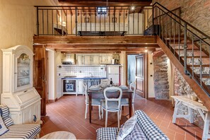 A spacious loft with a dining area, kitchen, and a staircase leading to an upper level.