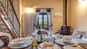 A dining table set with plates, glasses, and a bottle, a fireplace, and a staircase. - Apartment 'Il Belvedere' with Shared Pool, Private Terrace and Wi-Fi (Pian di Scò)