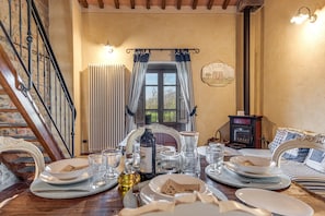 Una mesa de comedor con platos, vasos y una botella, una chimenea y una escalera.