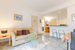 Una sala de estar con un sofá, una mesa de centro de vidrio y un comedor con una mesa y sillas.