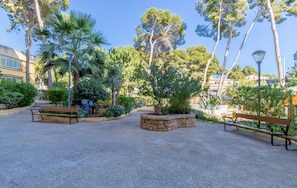 An outdoor area with benches, stone planters, and trees.