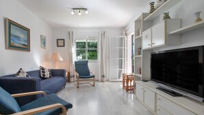 Un salon avec un canapé, des fauteuils, un téléviseur et une bibliothèque.