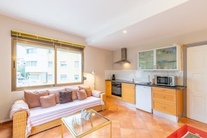 A compact living space with a sofa, kitchenette, and large windows.