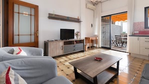 Una sala de estar con sofá, mesa de centro, televisor y comedor con sillas y mesa.
