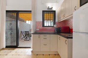 A kitchen with white cabinets, a red microwave, and a window with bars. - Apartment 'Ole Playa' with Sea View, Wi-Fi and Air Conditioning (Benalmadena)