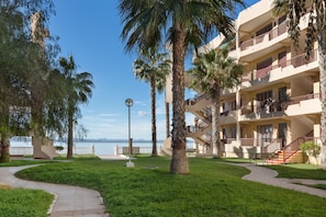 A hotel with a pool, palm trees, and a view of the sea.