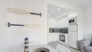 Une cuisine moderne avec des armoires blanches, un four encastré et un réfrigérateur.