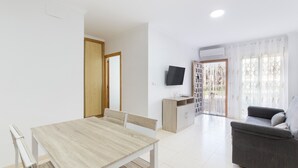 Una sala de estar moderna con una mesa de comedor, un sofá y un televisor montado en la pared.