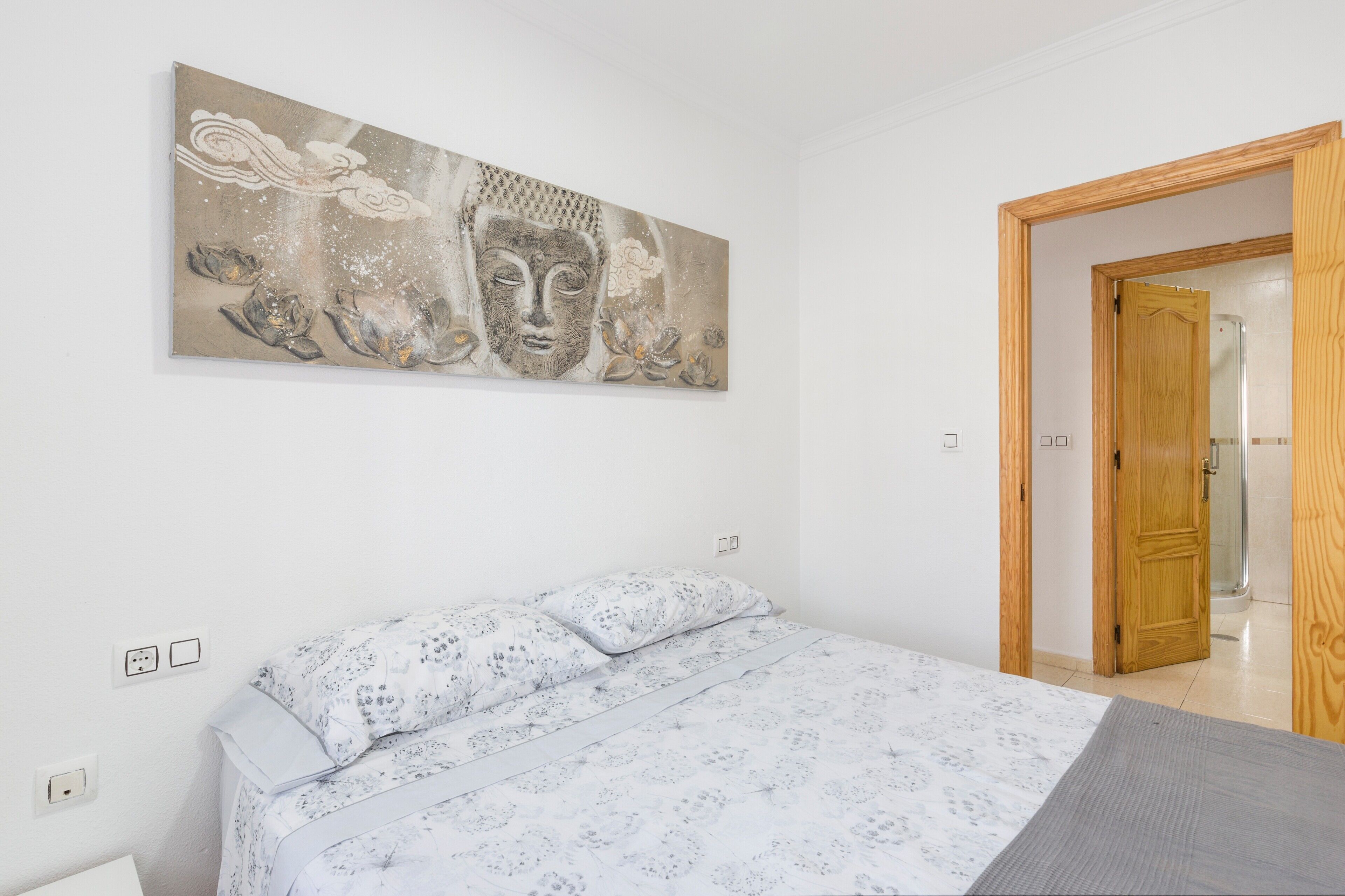 Une chambre à coucher avec un lit, une porte en bois et une œuvre d’art accrochée au mur.