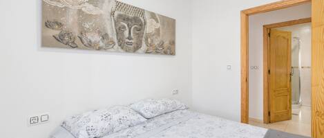 Une chambre à coucher avec un lit, une porte en bois et une œuvre d’art accrochée au mur.