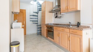 Una cucina con mobili in legno, un forno in acciaio inossidabile, un forno a microonde integrato e un lavello in acciaio inossidabile.