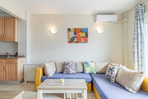 A modern living room with a sofa, a coffee table, and a kitchen area with cabinets and an air conditioning unit. - Apartment 'Penthouse Moraira Centrum' with Private Terrace, Wi-Fi and Air Conditioning (Moraira)