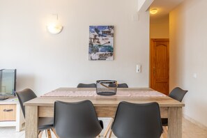 A dining area with a wooden table, black chairs, a painting on the wall, and a television on the left. - Apartment 'Penthouse Moraira Centrum' with Private Terrace, Wi-Fi and Air Conditioning (Moraira)