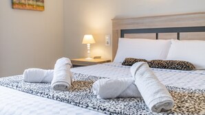 Un letto rifatto con cura, con copriletto decorato, una testiera e una lampada da comodino.