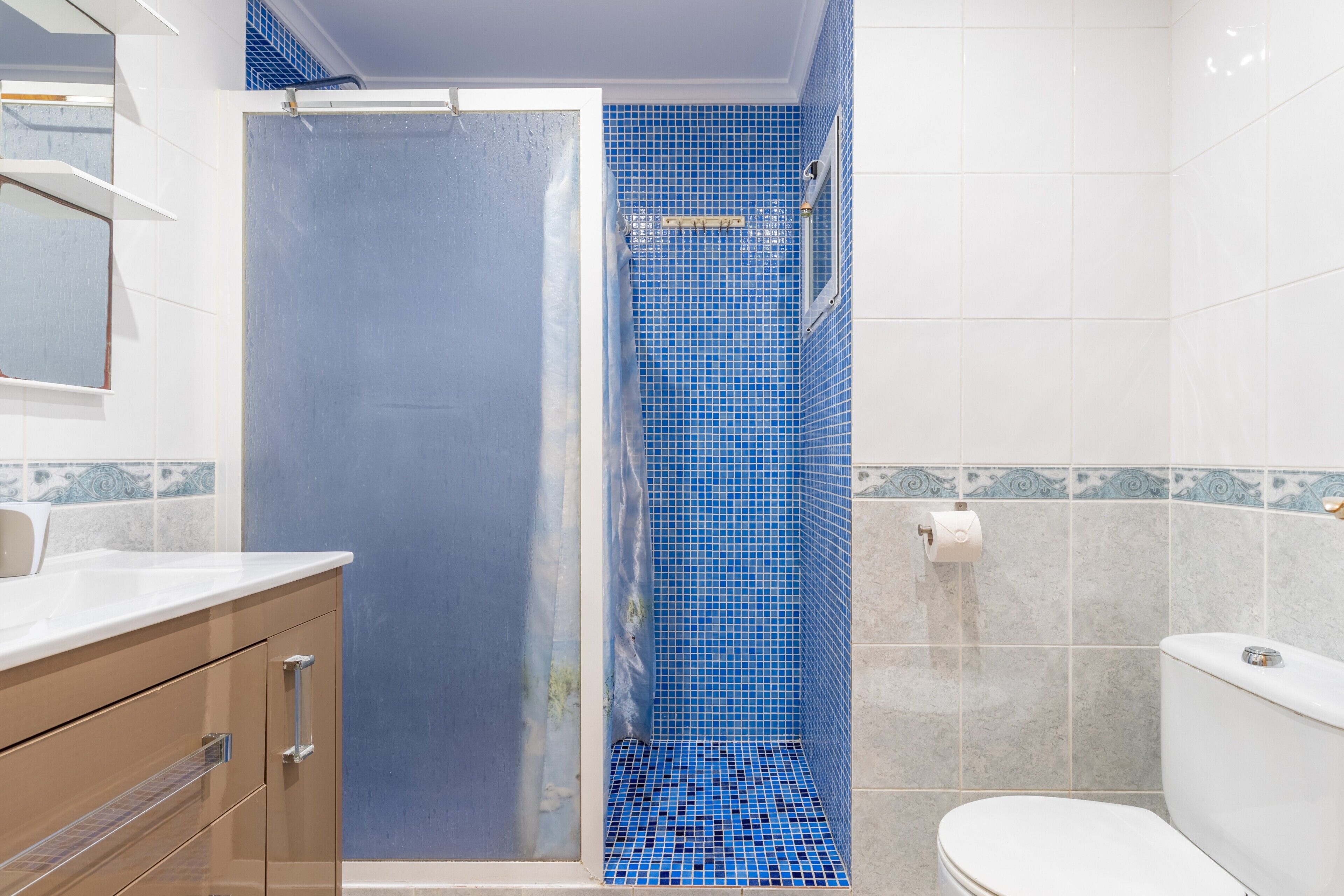 A bathroom with a shower, a toilet, and a sink.