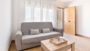 A neutral-toned sofa with cushions, a wooden coffee table with a tray, and a wooden door with a glass panel. - Apartment 'Arena De 2 Mares' with Sea View, Shared Pool and Private Terrace (La Manga)