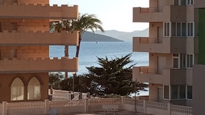 A multi-story building with balconies, a palm tree, and a view of the sea. - Apartment 'Arena De 2 Mares' with Sea View, Shared Pool and Private Terrace (La Manga)