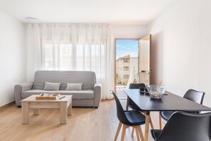 A modern living room with a sofa, coffee table, and dining area with chairs and a table. - Apartment 'Arena De 2 Mares' with Sea View, Shared Pool and Private Terrace (La Manga)