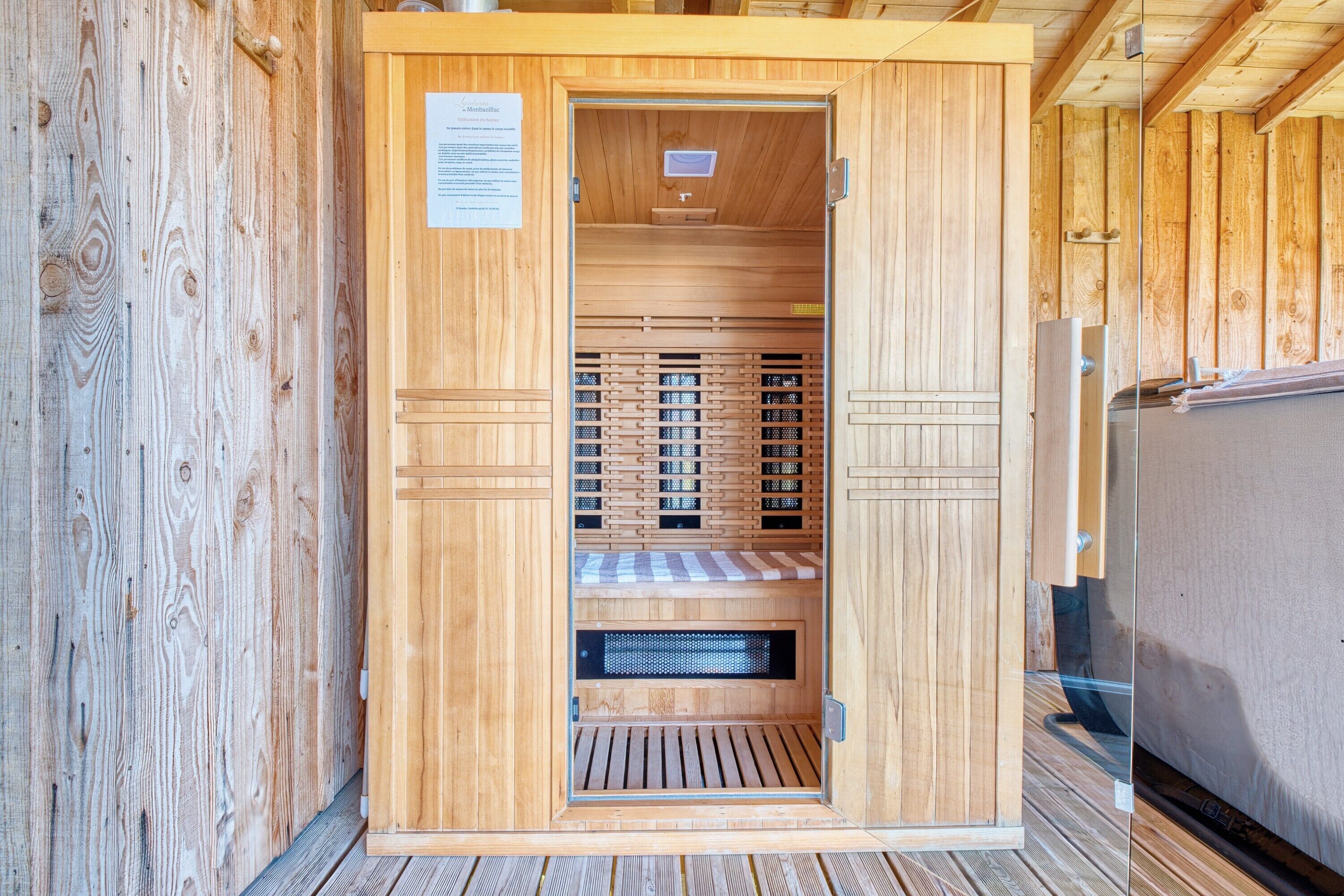 Un sauna avec des murs et des bancs en bois, un système de ventilation et une porte avec une pancarte.
