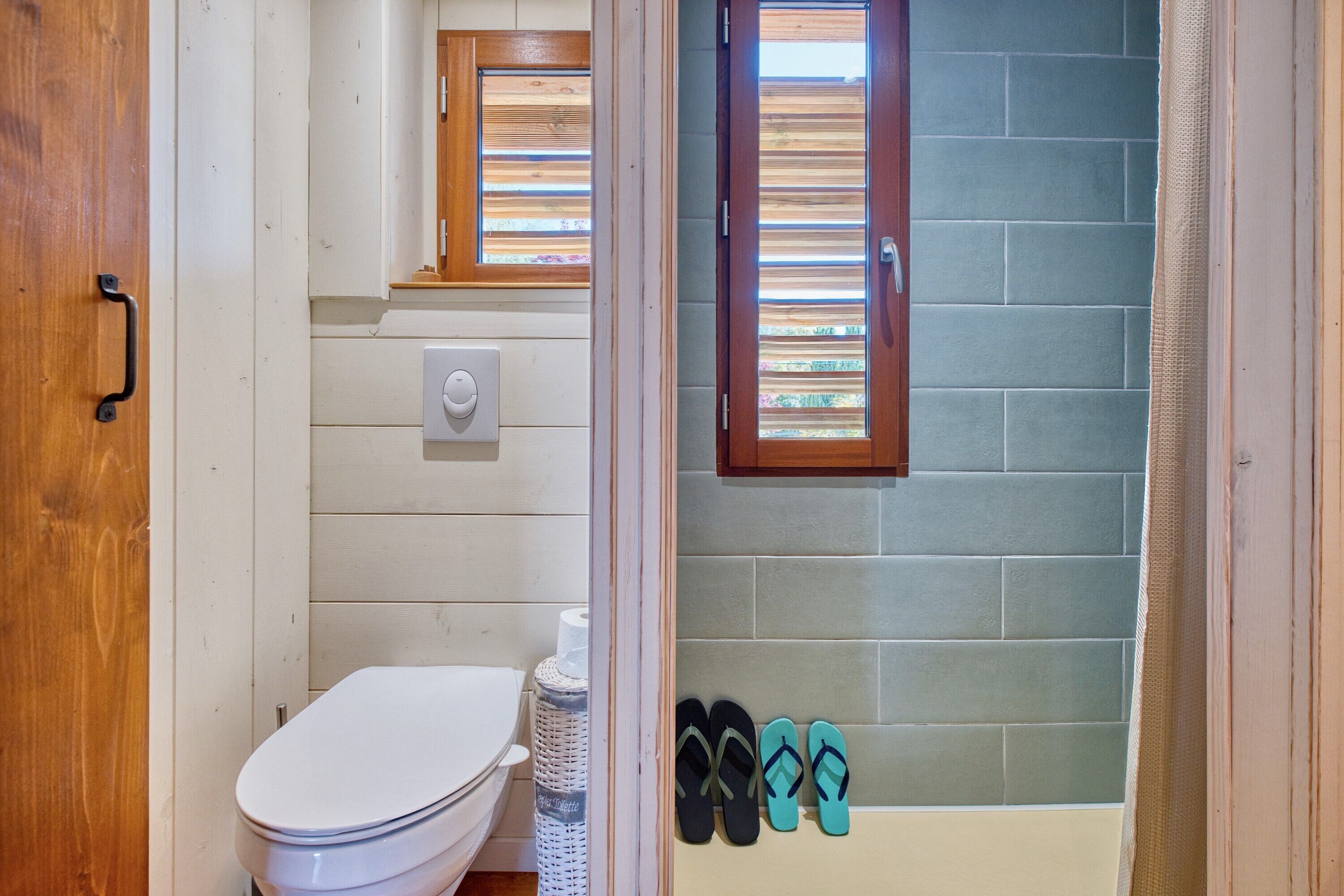A bathroom with a toilet, a window, a towel rack, and a shower area.