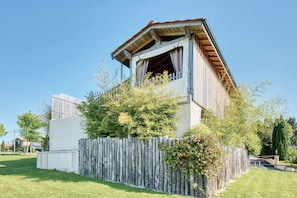 A rustic building with a wooden fence, a balcony, and a clear sky.
