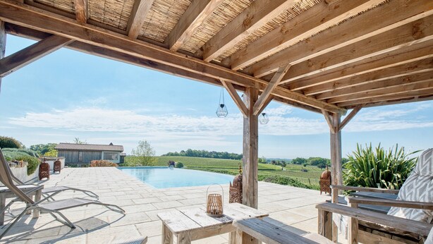 A wooden pergola with a pool, outdoor seating, and a view of the countryside. - Cabin 'Muscadelle' with Shared Pool, Wi-Fi and Air Conditioning (Monbazillac)