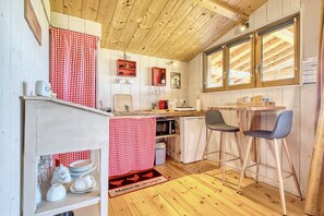 Une cuisine compacte dotée de meubles en bois, d’un four à micro-ondes, d’un petit réfrigérateur et d’un coin repas avec deux tabourets de bar.