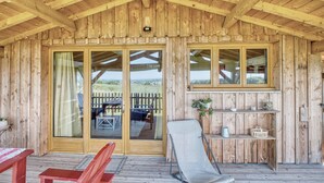 A wooden cabin with a covered porch, large sliding glass doors, and a deck with outdoor furniture. - Cabin 'Muscadelle' with Shared Pool, Wi-Fi and Air Conditioning (Monbazillac)