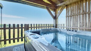 Un jacuzzi con una terraza de madera y una valla de madera al fondo.