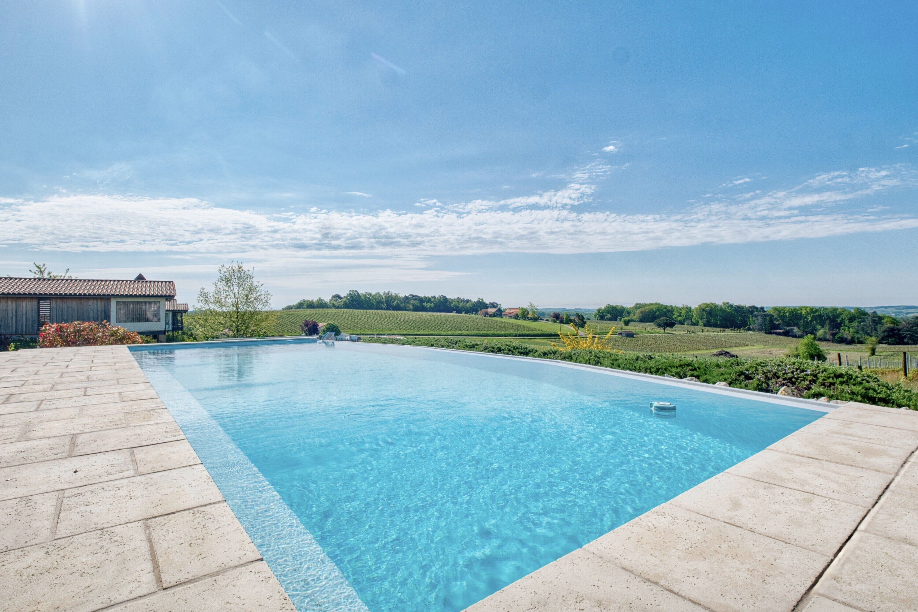 A swimming pool with a clear blue water surface, surrounded by a paved deck.