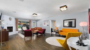 A modern living room with a fireplace, leather sofas, and a round rug. - 70s House Fun 6 Bedroom Pool Game Room (Round Rock)