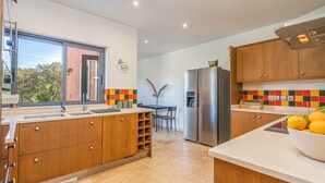 Eine moderne Küche mit Holzausstattung, einem Edelstahlkühlschrank und einem großen Fenster.