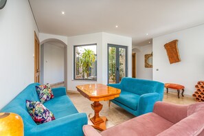 Una sala de estar moderna con sofás azul y rosa, una mesa de centro de madera y un espejo grande en la pared.