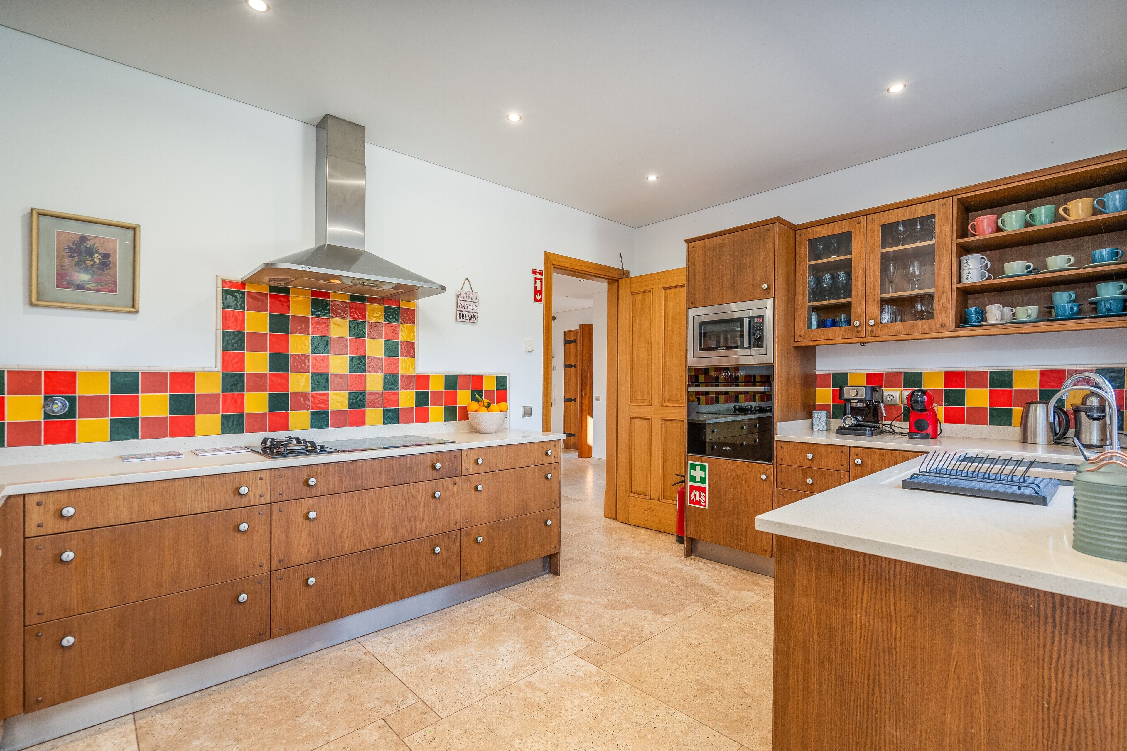 Une cuisine moderne avec des meubles en bois, une hotte en acier inoxydable et un pare-feu coloré.