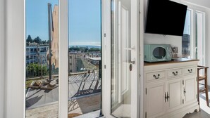A room with a sliding glass door leading to a balcony, a flat-screen TV mounted on the wall, and a vintage-style microwave on a cabinet. - Apartment 'Agriturismo Le Pale - Giuli 2' with Sea View, Wi-Fi and Air Conditioning (Bogliasco)