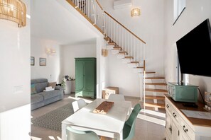 A modern living space with a staircase, a dining area, and a green cabinet.
