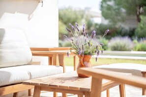 A wooden table with a potted lavender plant, a white sofa, and a wooden bench in a bright outdoor setting. - Villa 'Las Estrellas Cala Llombards' with Sea View, Wi-Fi and Air Conditioning (Cala Llombards)