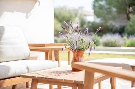 A wooden table with a potted lavender plant, a white sofa, and a wooden bench in a bright outdoor setting.. Villa 'Las Estrellas Cala Llombards' with Sea View, Wi-Fi and Air Conditioning