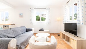 Een moderne woonkamer met een bank, een ronde tafel, een televisie en een raam met gordijnen.