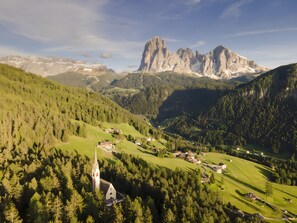 A mountainous landscape with a church, houses, and a prominent rocky peak.