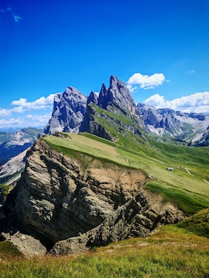 A mountainous landscape with a prominent rocky peak and a valley with green fields. - Apartment 'Apartments Emilia 2' with Mountain View, Balcony and Wi-Fi (Ortisei)