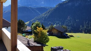 Ein Holzbalkon mit Blick auf eine gebirgige Landschaft unter klarem Himmel.