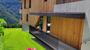 A modern wooden building with a balcony, surrounded by a well-maintained lawn and a mountainous backdrop. - Apartment 'Apartments Emilia 3' with Mountain View, Balcony and Wi-Fi (Ortisei)
