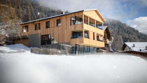 A modern wooden building with multiple balconies and large windows, surrounded by snow and mountains. - Apartment 'Apartments Emilia 3' with Mountain View, Balcony and Wi-Fi (Ortisei)