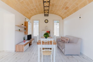 A living room with a wooden table, white chairs, a beige sofa, and a fireplace. - Villa 'Dimora Balu'' with Sea View, Wi-Fi and Air Conditioning (Parabita)