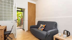 Un salon moderne avec un canapé gris, un plancher en bois et une petite table sur laquelle se trouve une bouilloire.